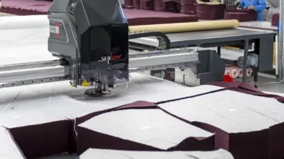 SERKON Heavy-duty automated fabric cutting machine slicing through multiple layers of dark textile at Istanbul Factory.