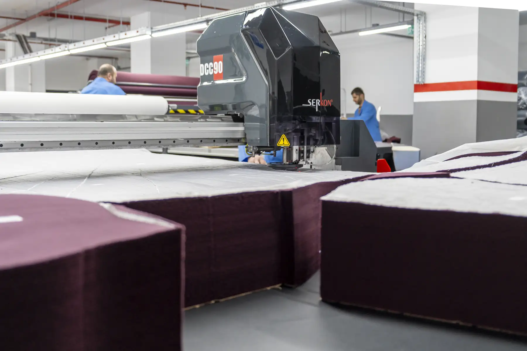 Professional cutting table with stacked fabric layers being cut precisely.