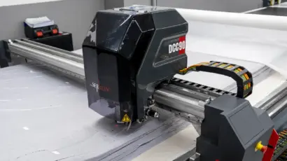 Close-up of a high-speed automated cutting head slicing through layered fabric.