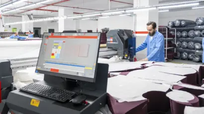 Technician monitoring the CAD/CAM software interface that controls the automated fabric cutter.