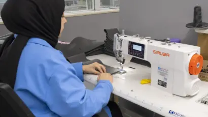 Female employee operating a modern, computerized sewing machine.