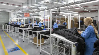 Wide view of the dedicated quality control and packaging line at Istanbul Factory, with workers inspecting black garments.