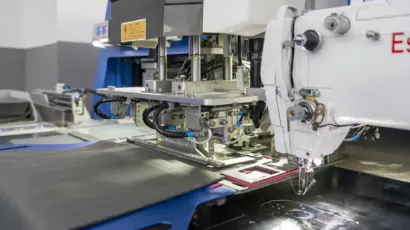 Close-up of an automated pocket setting and stitching machine in operation.