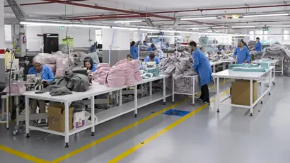Production team working at large tables sorting and organizing cut fabric pieces.