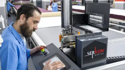 Istanbul Factory technician operating the digital control panel of an automated fabric cutting machine.