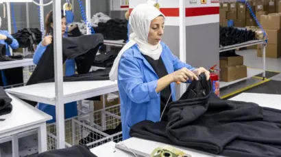 Female quality control inspector carefully examining and folding a black jacket at her dedicated workstation.