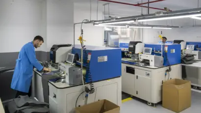 Worker in a blue uniform operating fabric spreading and processing equipment on the factory floor.