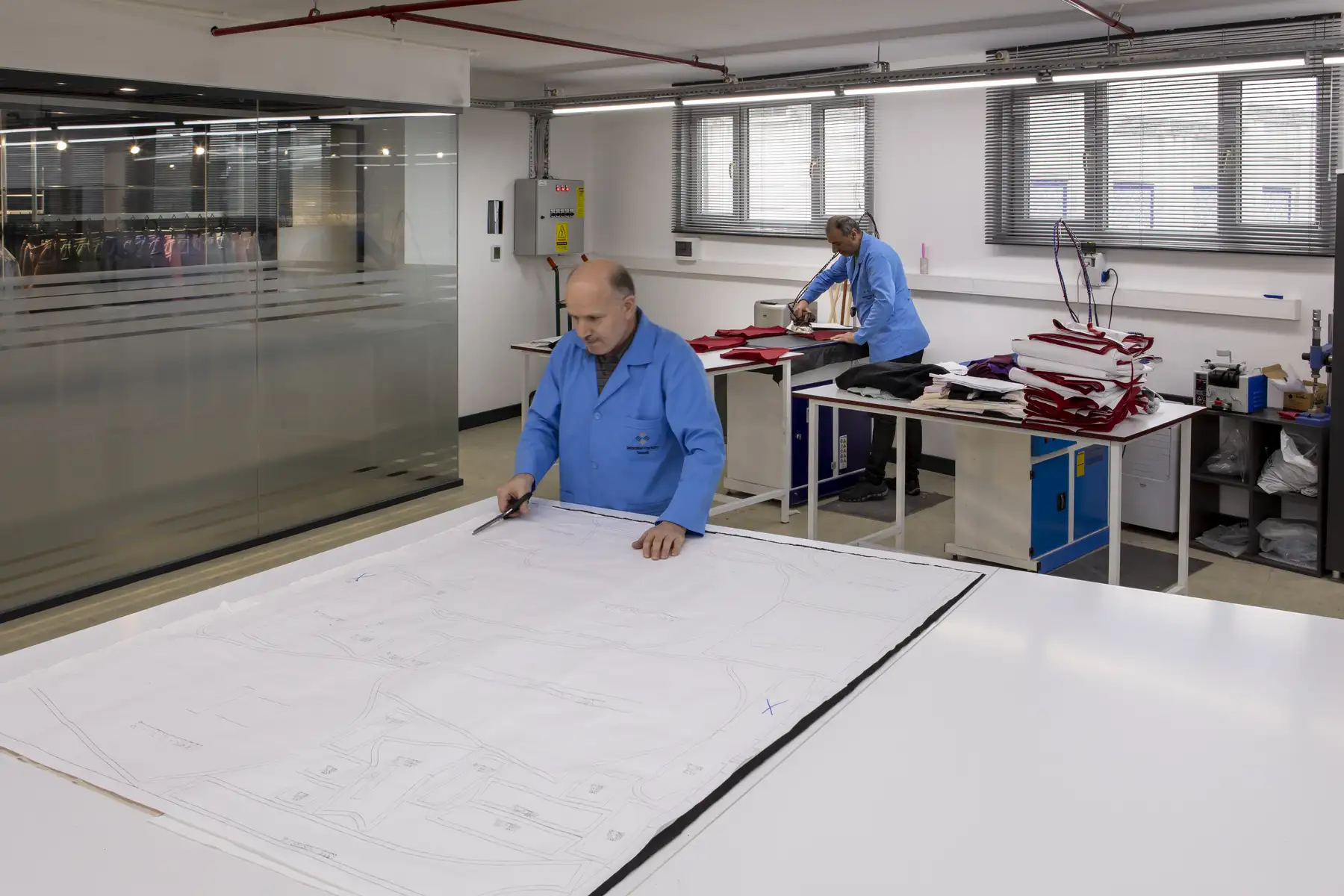 Pattern maker creating garment patterns on a large cutting table.